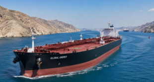 Commercial oil tanker navigating through the narrow waters of the Strait of Hormuz under a clear sky, representing global energy trade pathways.
