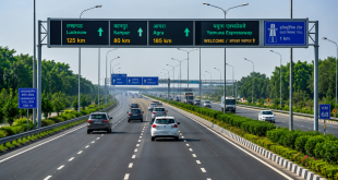 Multi-lane modern expressway in Uttar Pradesh with clear road markings, digital overhead signage, and green belts, demonstrating India's high-speed highway connectivity network.