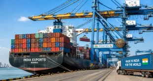 Container ship loaded with export cargo docked at a modern Indian seaport with cargo cranes operating under a clear sky.