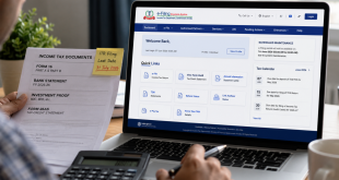 A close-up view of an individual checking financial documents alongside a laptop screen displaying the official Indian income tax e-filing dashboard.